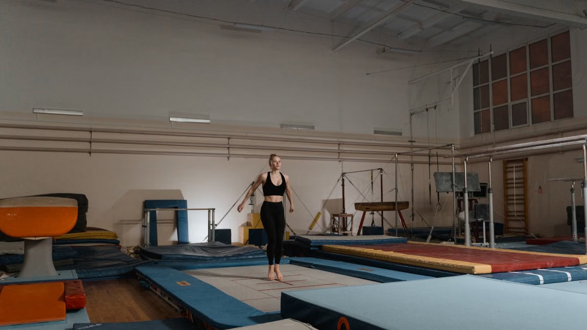 A young female gymnast practicing on gymnastics equipment indoors, showcasing balance and agility.